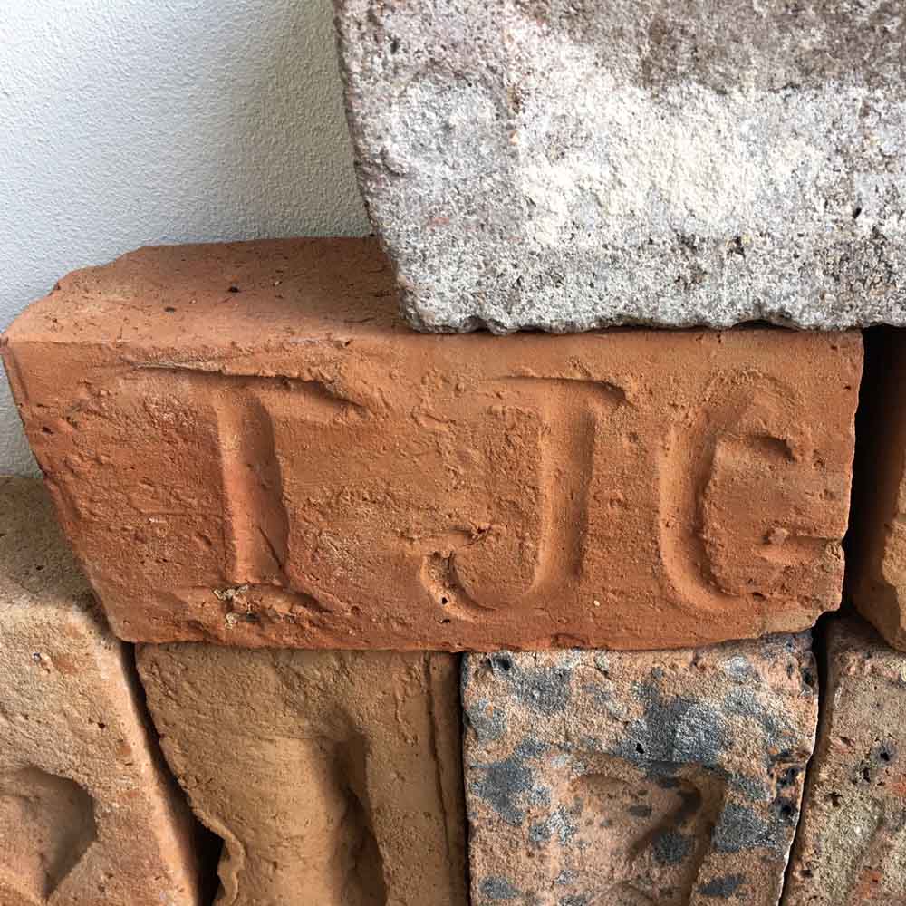 Initials etched into an irreplaceable handmade heritage brick immortalise the worker.